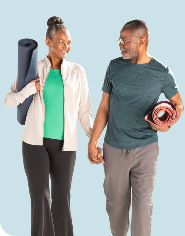 Image of an older couple walking with yoga mats tucked under their arms and holding hands